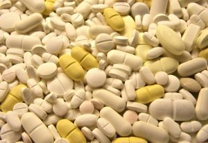 Close-up of assorted medication pills background with a variety of yellow and white tablets, capsules, and drugs for pain relief, antibiotics, and dosage treatment in a pharmacy setting
